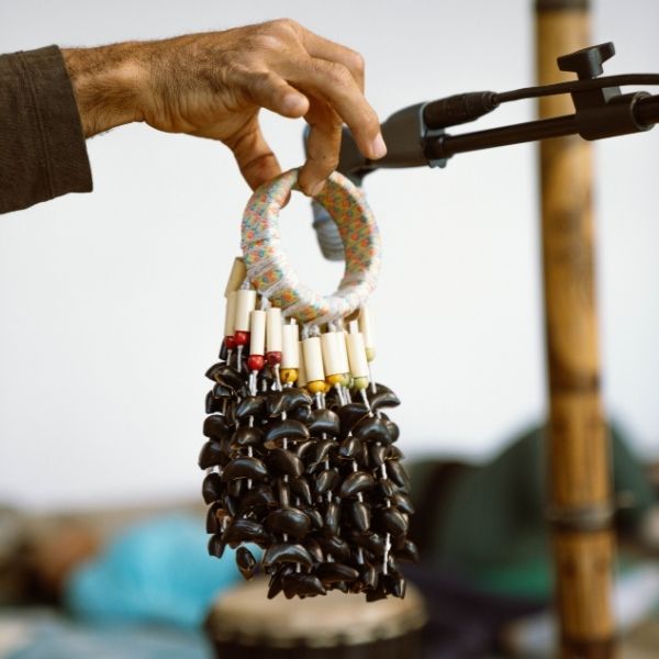 A facilitator holding agogo bells and other instruments during a Live Community REset Experience, enriching the meditative sound healing session.