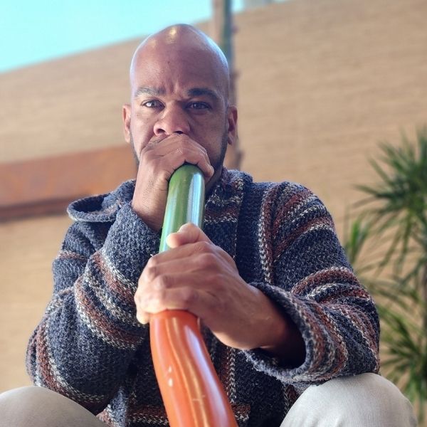 A Healing Sanctuary facilitator playing the didgeridoo during a Live Community REset Experience, enhancing the meditative atmosphere with deep, resonant sound vibrations.