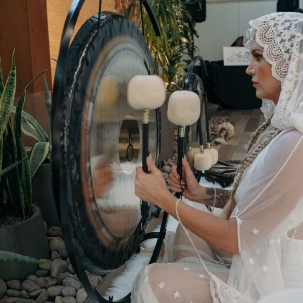 A Healing Sanctuary facilitator playing the gong during a Live Community REset Experience, creating deep resonant vibrations to enhance meditation and relaxation.