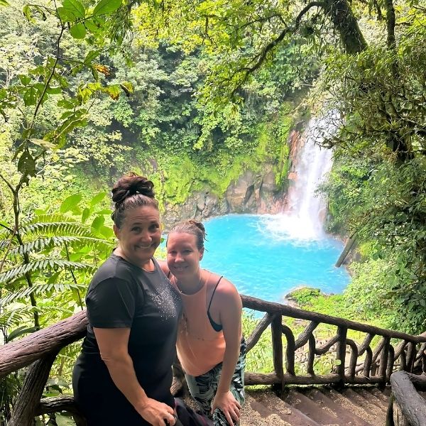 Guests standing near a breathtaking blue waterfall in the lush Costa Rican jungle during The Healing Sanctuary’s Tropical Retreat.